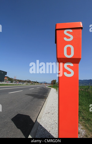 SOS orange sign next to a road by beautiful weather Stock Photo