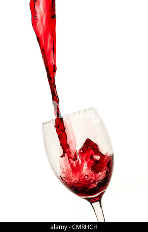 Glass filled with a large stream of red wine on white background Stock Photo