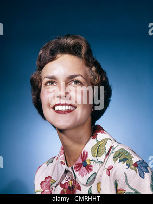 1960s SMILING WOMAN IN WHITE PRINT DRESS LOOKING UP STUDIO Stock Photo
