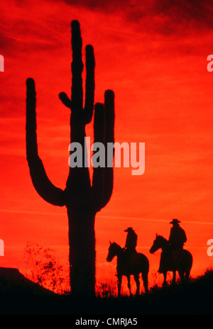 1980s SILHOUETTE TWO COWBOYS ON HORSEBACK BY SAGUARO CACTUS Stock Photo