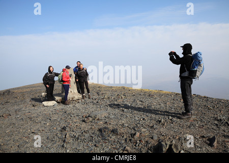 Party of fell walkers being photographed at  the summit of Skiddaw, Cumbria, NW England, UK Stock Photo