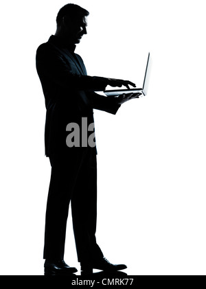 one caucasian business man computing computer laptop silhouette standing Full length in studio isolated on white background Stock Photo