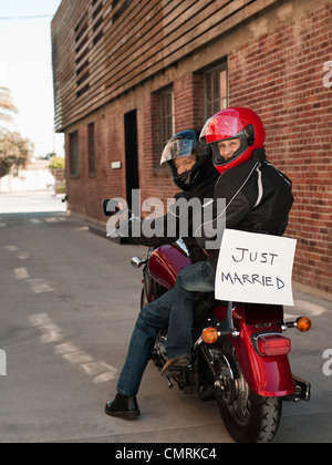 Caucasian couple riding on motorcycle with Just Married sign Stock Photo