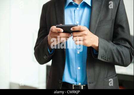 Black businessman text messaging on cell phone Stock Photo