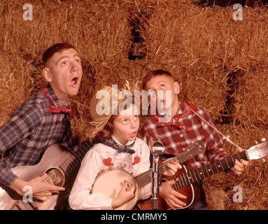 3 SIBLINGS CHILDREN YOUTH ADOLESCENTS PLAYING INSTRUMENTS BANJO GUITAR GUITARS 1960 1960s RETRO COUNTRY RURAL Stock Photo