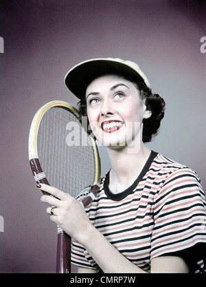 1950s SMILING BRUNETTE WOMAN HOLDING TENNIS RACKET WEAR STRIPED SHIRT CAP Stock Photo