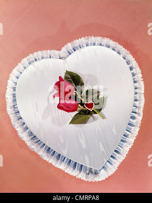 1960 1960s RETRO HEART SHAPED BOX COVERED WITH BLUE SATIN LACE TRIM TWO RED ROSES VALENTINE ROMANCE Stock Photo