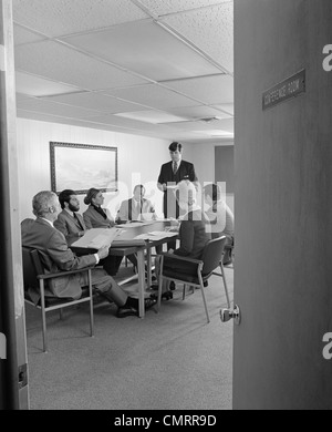 1970s GROUP 7 EXECUTIVE BUSINESS PEOPLE  CONFERENCE TABLE VIEWED THROUGH OPEN DOOR Stock Photo