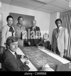 1970s PORTRAIT 6 BUSINESS PEOPLE MEN & WOMEN AROUND TABLE WITH BLUEPRINTS Stock Photo