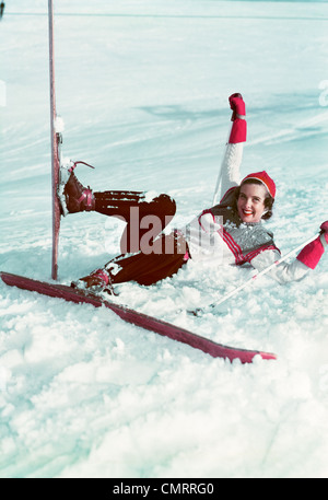 1940s 1950s WOMAN ON SKIS FALLING IN SNOW LOOKING AT CAMERA Stock Photo