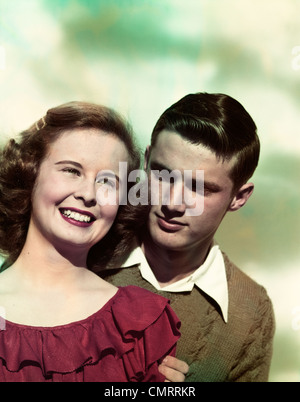 1940s 1950s PORTRAIT TEEN COUPLE GIRL SMILING BOY LOOKING OVER GIRL’S SHOULDER Stock Photo