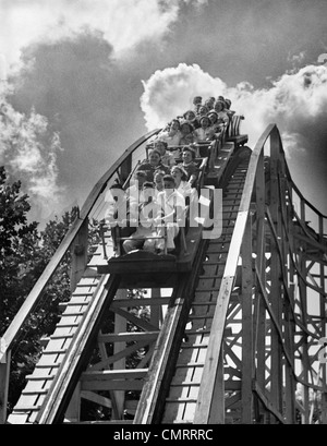 1950s GROUP OF TEENS ON ROLLER COASTER COMING DOWN TOP OF CREST OUTDOOR Stock Photo