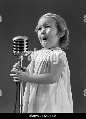 1940s LITTLE GIRL MAKING FACE SINGING INTO MICROPHONE Stock Photo