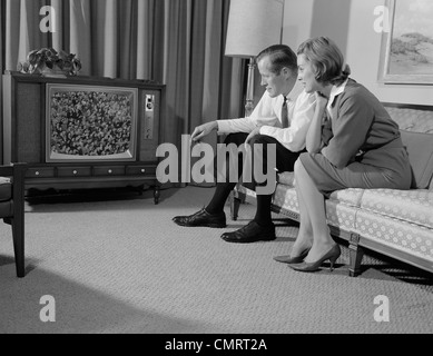 1960s COUPLE MAN WOMAN SITTING ON COUCH WATCHING TELEVISION Stock Photo