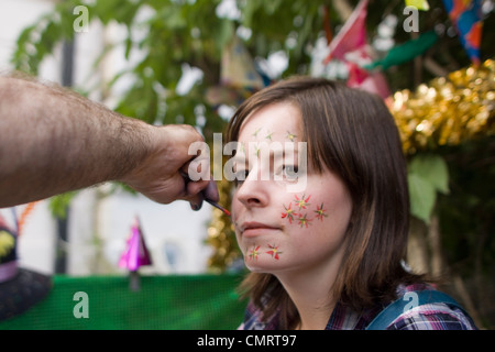 A reveler at the Notting Hill Carnival in London getting her face painted. Stock Photo