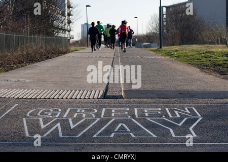 Greenway sign and path, for bikes, walking and jogging. View down path with group of runners and trees in background copy space. Stock Photo