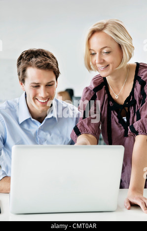 Two people using laptop and smiling Stock Photo