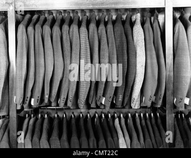 1940s RACK OF MEN'S WOOL JACKETS HANGING IN RETAIL STORE MEN'S FASHION CLOTHING SUITS Stock Photo