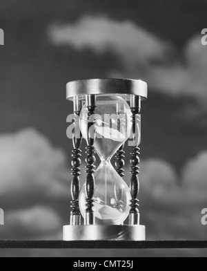 1950s HOURGLASS AGAINST BACKGROUND OF CLOUDS Stock Photo