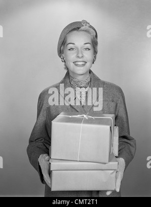 1950s FASHIONABLY DRESSED WOMAN HOLDING PACKAGES WRAPPED IN BROWN PAPER AND STRING Stock Photo