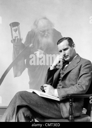 1930s MAN IN SUIT SEATED WITH BOOK IN LAP & PIPE IN HAND WITH PENSIVE LOOK WITH GRIM REAPER GHOSTED IN BACKGROUND Stock Photo