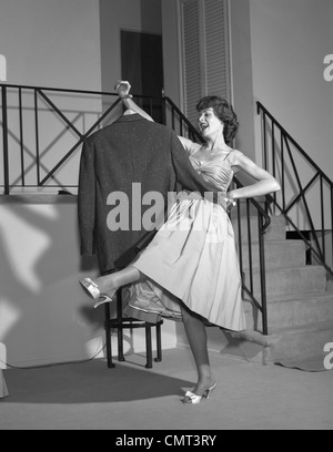 1960s WOMAN IN COCKTAIL DRESS DANCING WITH MAN'S EMPTY JACKET Stock Photo
