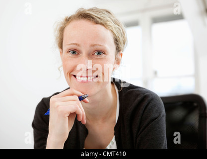 Portrait of smiling woman holding pen Stock Photo