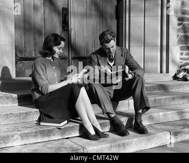 1940s YOUNG COUPLE SITTING ON STEPS WITH SCHOOLBOOKS AND PAPERS SMILING OUTDOOR Stock Photo