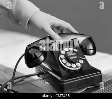 1940s WOMAN'S HAND PICKING UP PHONE RECEIVER Stock Photo