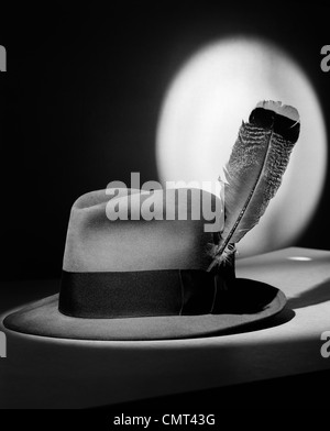 1940s FEDORA HAT WITH FEATHER IN BAND IN SPOTLIGHT SYMBOLIC FEATHER IN YOUR CAP Stock Photo