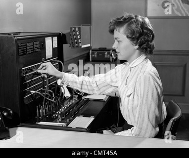 1950s WOMAN OFFICE TELEPHONE SWITCHBOARD RECEPTIONIST OPERATOR WEARING HEADSET ANSWERING TRANSFERRING CALL Stock Photo