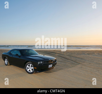 retro car on sandy beach in USA California at sunset with sea and horizon Stock Photo