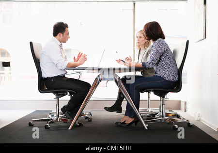 Three business people discussing at conference table Stock Photo