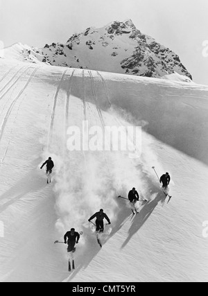 1920s 1930s FIVE MEN SKIING DOWN SNOW COVERED ALPS SWITZERLAND Stock Photo
