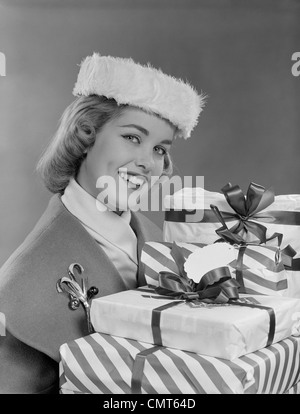 1950s SMILING WOMAN IN FUR HAT HOLDING WRAPPED CHRISTMAS PRESENTS Stock Photo