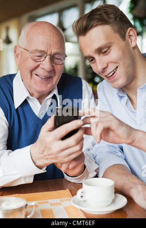 Elderly and young man using mobile phone Stock Photo