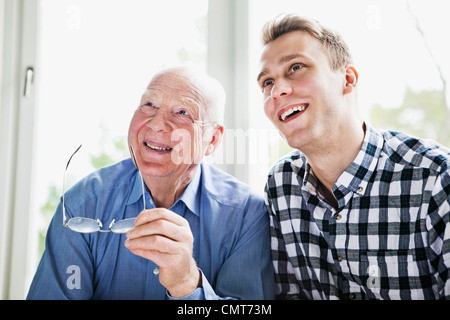 Happy elderly man and guy looking out through window Stock Photo
