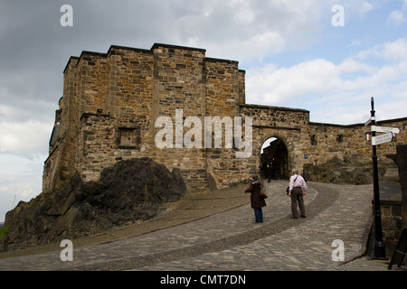 Old couple inside Edinburgh Castle in Scotland, climbing up a paved path that leads to a part of the building at a height Stock Photo