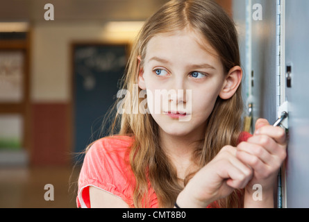 Girl (12-13) lost in thought opening padlock Stock Photo