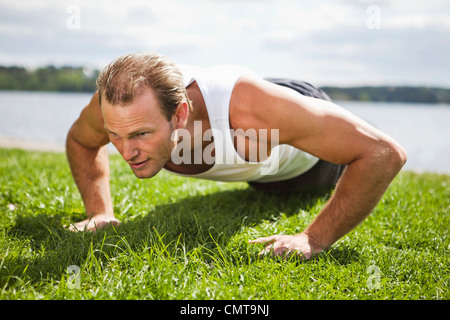 Man doing push-ups on grass Stock Photo