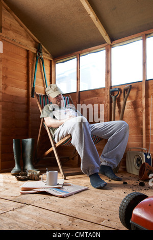 Man sitting in deckchair falling asleep in the shed Stock Photo