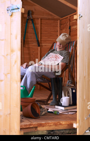 Man sitting in deckchair falling asleep in the shed Stock Photo