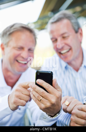 Friends laughing and using cell phone Stock Photo