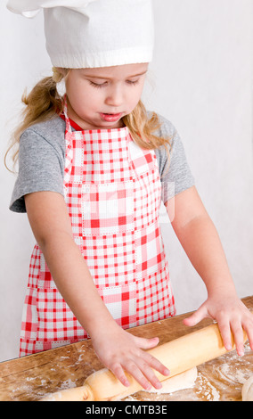 the girl in the hat chef rolls the dough Stock Photo