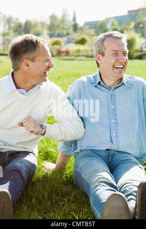 Two smiling men sitting on grass Stock Photo