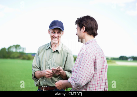 Two men smiling and holding roots Stock Photo