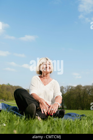 Senior woman sitting on grass Stock Photo