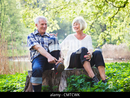Senior couple sitting on tree stump Stock Photo