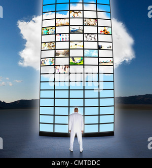 Mixed race businessman looking at towering monitors Stock Photo