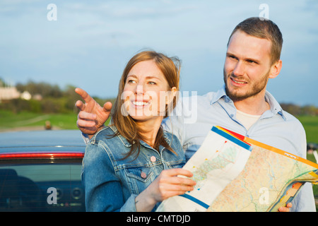 Woman holding map with man pointing Stock Photo